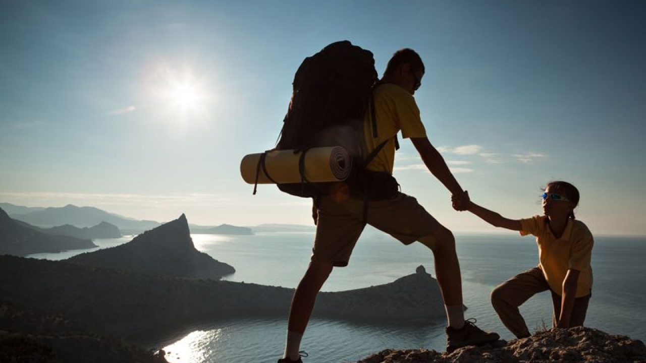 guy pulling up girl in a yellow shirt rock climbing